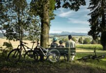 Das richtige Kinderbike finden: Der Ratgeber vom Laufrad bis zum Fully Familie mit Kinderbikes macht Pause auf einer Bank in Lussy bei Romont