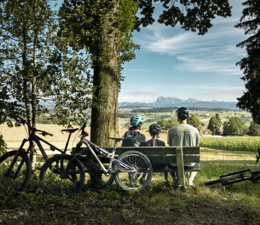 Das richtige Kinderbike finden: Der Ratgeber vom Laufrad bis zum Fully Familie mit Kinderbikes macht Pause auf einer Bank in Lussy bei Romont
