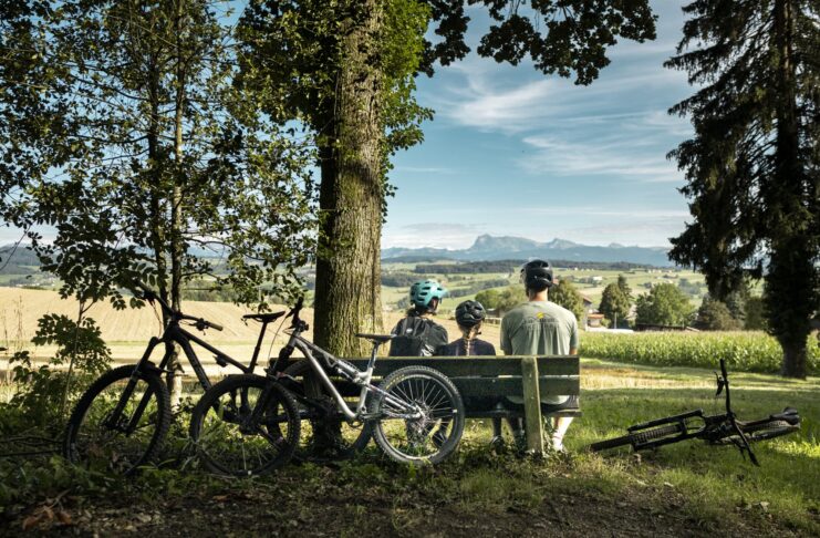Das richtige Kinderbike finden: Der Ratgeber vom Laufrad bis zum Fully Familie mit Kinderbikes macht Pause auf einer Bank in Lussy bei Romont